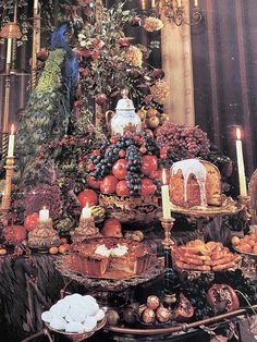 a table topped with lots of different types of cakes and pastries next to candles