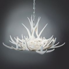 a white chandelier hanging from a chain with lights on it and antler stems