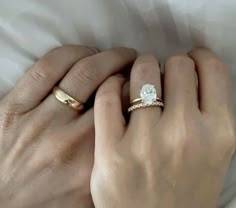 two hands holding each other while one holds the other's hand with an engagement ring