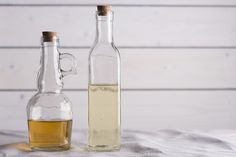 two glass bottles filled with liquid sitting on top of a bed next to each other