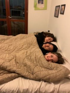 two women are laying in bed and smiling