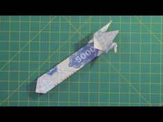 an origami airplane made out of money on a green cutting mat with scissors