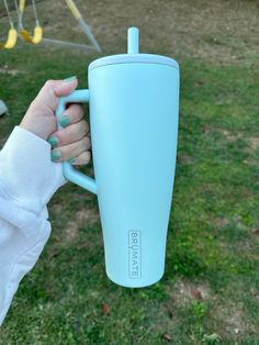 a person holding a blue coffee cup in their hand with the lid up and handle down