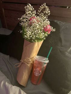 a starbucks drink and some flowers on a bed