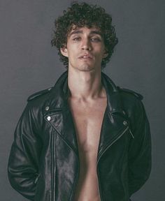 a shirtless man in a black leather jacket posing for the camera with his hands on his hips