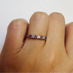 a woman's hand with a pink and white diamond ring on her left hand