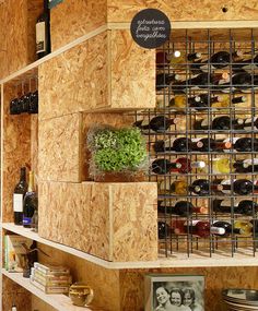 a wine rack filled with lots of bottles next to a wall mounted shelf full of glasses