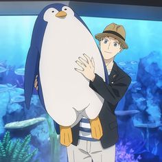 a man holding a penguin in front of an aquarium