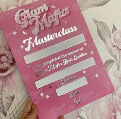 a person holding up a pink card with the words glam magic master class on it