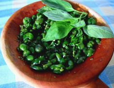 a wooden bowl filled with green vegetables on top of a table