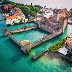 an aerial view of a castle in the middle of water with buildings on both sides