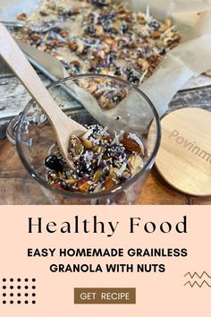 granola with nuts in a glass bowl next to a wooden spoon on a table