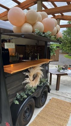 an old truck is decorated with balloons and greenery for a party or outdoor event