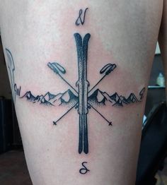 a cross tattoo with skis and mountains on the back of his leg is shown