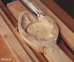 a wooden spoon and knife rest on top of a cutting board in a box with other woodworking tools