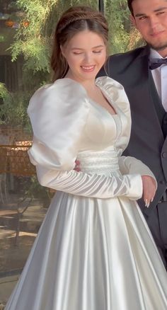 a man in a tuxedo standing next to a woman in a wedding dress