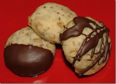 three cookies with chocolate drizzled on them sitting on a red table top