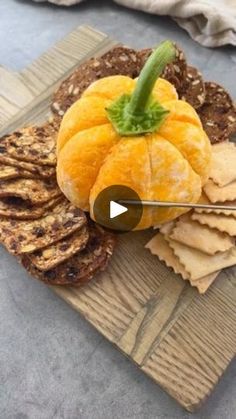 an orange sitting on top of a cutting board next to crackers