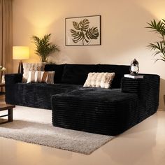 a living room with black couches and white rugs on the floor next to potted plants