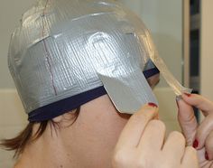 a woman is cutting her hair with a pair of scissors in front of her face