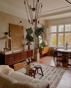 a living room filled with lots of furniture and a tall plant hanging from the ceiling