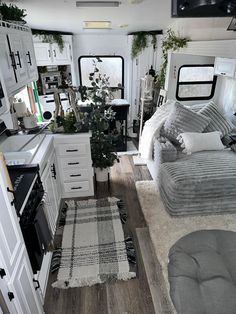 the interior of a camper with white and gray decor, including bedding, rugs, cabinets, drawers, stove top oven and microwave