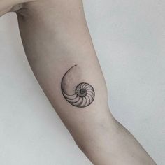 a black and white photo of a nauti shell tattoo on the left inner arm