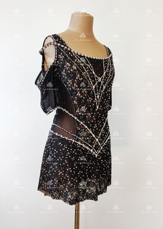 a mannequin wearing a black and white dress with beading on the shoulders