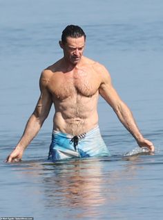 a shirtless man wading in the ocean