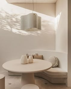 a white table sitting under a light fixture next to a couch and ottoman in a living room