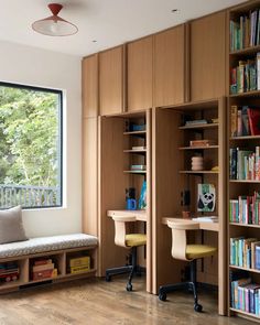 a room with bookshelves, desks and chairs in front of a window