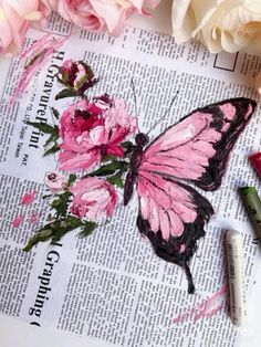 a pink butterfly sitting on top of a newspaper next to some crayons and flowers