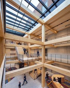 people are walking around in a large building with wood beams and glass roofing on the top floor