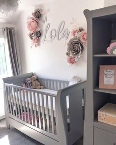 a baby's room with a crib, bookcase and flowers on the wall