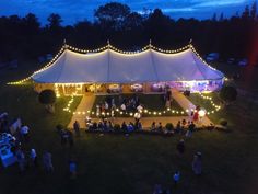 an overhead view of a large tent with lights on it and people standing in the grass