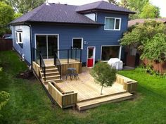 a blue house with steps leading up to the front door and deck area in the yard