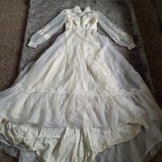 an old white dress is laying on the floor next to a gray blanket and carpet