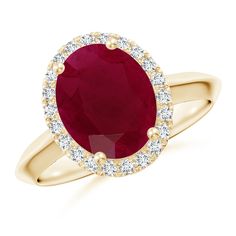 an oval shaped ruby and diamond ring in yellow gold with diamonds around the shans