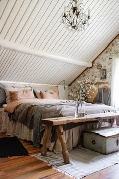 an attic bedroom with a bed, dresser and table in the corner that is made out of wood