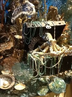 an assortment of sea life displayed in a glass case with beads and chains hanging from it's sides