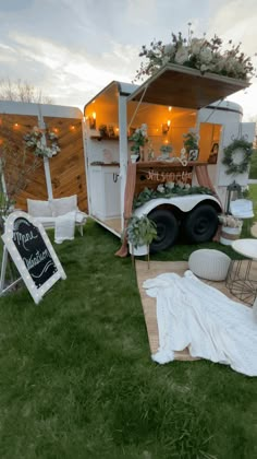 an outdoor event with white furniture and decorations on the grass, including a mobile bar