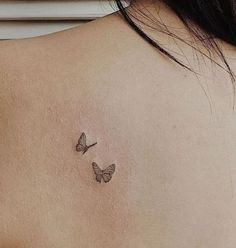 the back of a woman's shoulder with two small butterflies on her left side