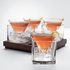 four glasses filled with different types of cocktails on top of ice cubes in front of a white background