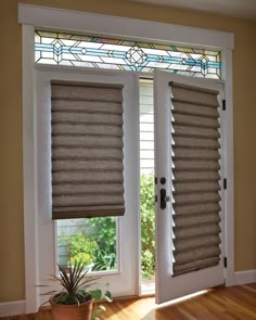 an open window with blinds on it and a potted plant next to the door