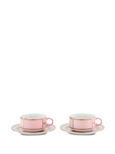 two pink tea cups and saucers with gold rims on each side, against a white background