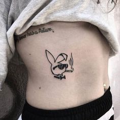 a woman's stomach with a cartoon character tattoo on her left side ribcage