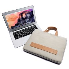 an open laptop computer sitting on top of a white table next to a bag and purse