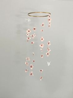 a wind chime with pink flowers hanging from it's side on a wall