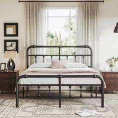 a bedroom with a bed, dressers and window in the background on a rug