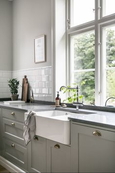 a kitchen with white cabinets and gray counter tops, along with a window over the sink